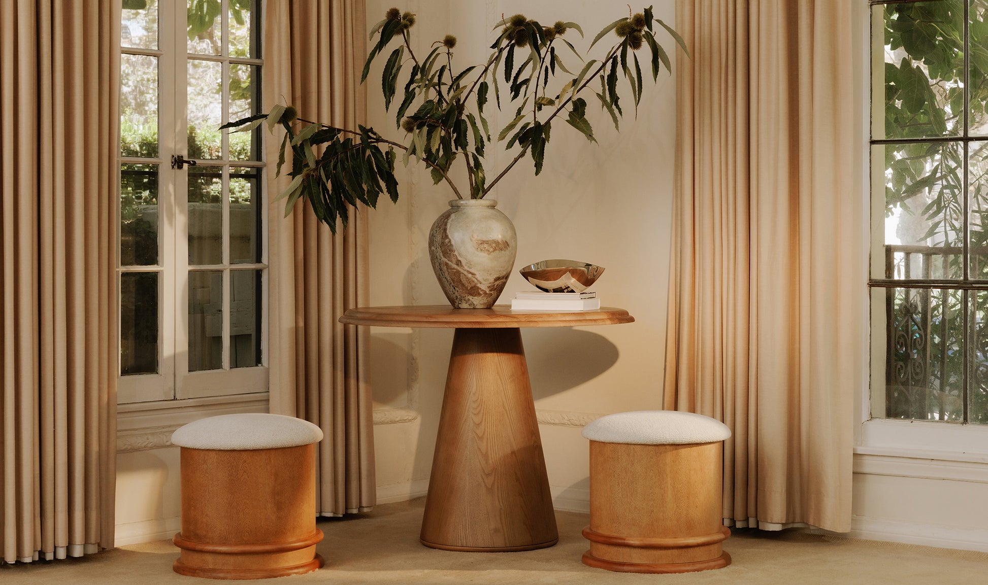 Wooden table with decorative items in a room with curtains and windows.